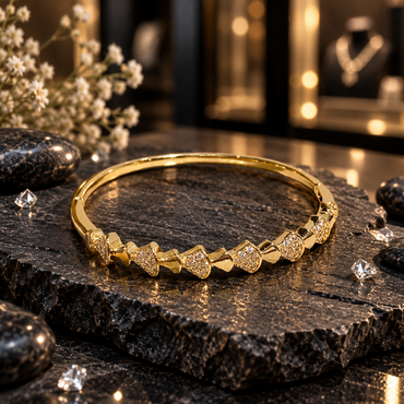 Gold-tone bangle with repeating fan-shaped motifs, small clear accents, polished-looking angular details and a smooth back section.
