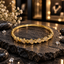 Gold-tone bangle with repeating fan-shaped motifs, small clear accents, polished-looking angular details and a smooth back section.