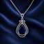 Royal blue sapphire CZ pear-cut teardrop bow pendant necklace in silver-tone with double white CZ halo frame on fine wheat chain displayed on navy satin fabric
