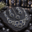 Royal blue oval and clear-accent jewellery set with a silver-tone swirl necklace, two drop earrings and matching chain maang tikka on dark slate.
