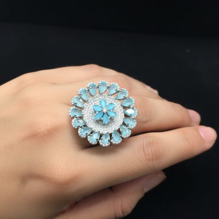 Close-up of a hand wearing a decorative ring with blue gemstones on a black background