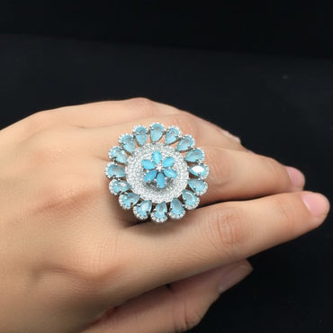 Close-up of a hand wearing a decorative ring with blue gemstones on a black background