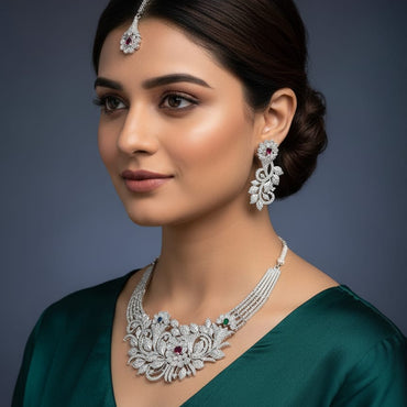 Woman wearing a silver necklace and earrings with a dark background