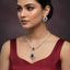 Woman wearing a diamond necklace and earrings with a maroon top against a dark background