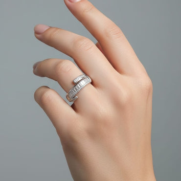 Hand wearing a silver ring on a gray background