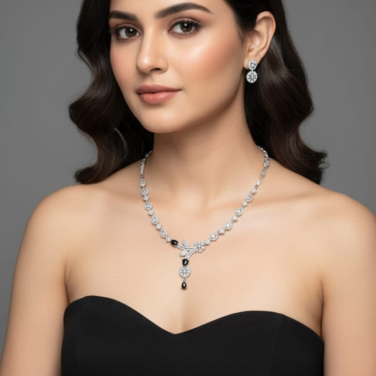 Woman wearing a black dress with a necklace and earrings on a gray background