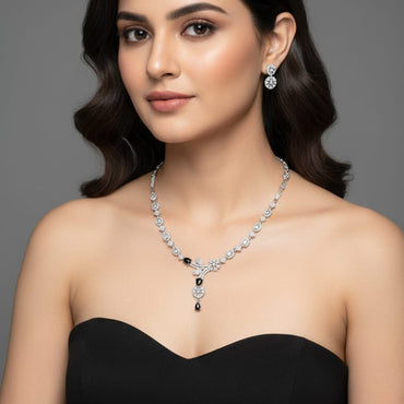 Woman wearing a black dress with a necklace and earrings on a gray background