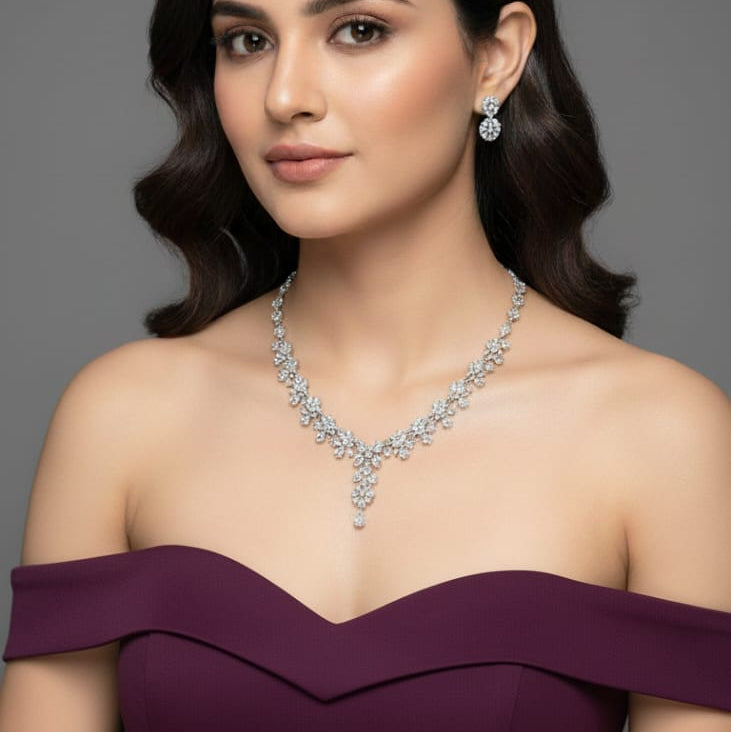 Woman wearing a purple off-shoulder dress with a diamond necklace and earrings on a gray background