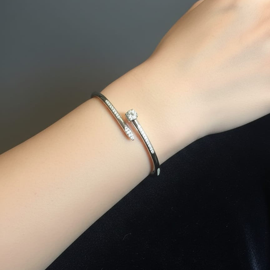 Close-up of a wrist wearing two silver bracelets against a dark background