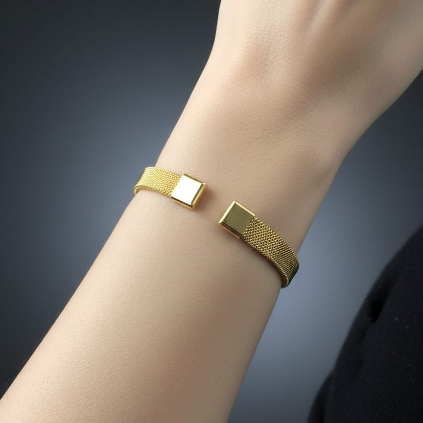 Gold bracelet on a wrist with a dark gradient background