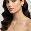 Woman wearing gold necklace and earrings on a plain background