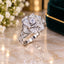 Silver All-White CZ 3D Rose Bloom Floral Solitaire Bridal Cocktail Ring on white marble surface with white flowers and green velvet ring box backdrop