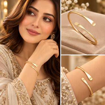 Model wearing a slim gold-tone open cuff bracelet with smooth flattened ends.