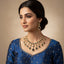 Woman wearing a gold necklace and earrings on a beige background