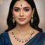 Woman wearing gold jewelry with blue stones on a neutral background