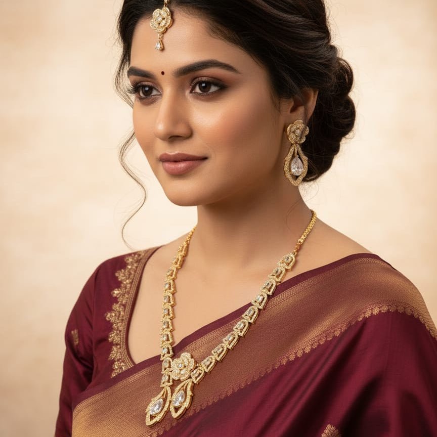Woman wearing a maroon saree with gold jewelry against a beige background