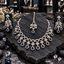 Silver-tone AD necklace with dark blue round halos, clear flower clusters and blue teardrop drops, displayed with matching chandelier earrings and maang tikka on dark slate.