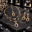 Gold-tone AD purple double-layer necklace with clear floral details and a leaf-bordered teardrop pendant, displayed with matching drop earrings and maang tikka on dark slate.