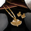 Antique Gold Ruby Pearl Mughal Rani Haar Long Necklace Earrings Set on black mirror surface with burgundy gold brocade backdrop showing double-strand gold ball bead and seed pearl chain with fan filigree pendant ruby red CZ emerald green CZ seed pearl fringe gold tassel drops and matching temple jhumka earrings