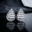 Baguette CZ Teardrop Stud Earrings with Round Pavé Border in gold-tone plating flat lay on dark grey stone surface with dark silk backdrop showing pair of open teardrop studs with tiered channel-set baguette CZ interior and micro-pavé round CZ border with mirror reflections below