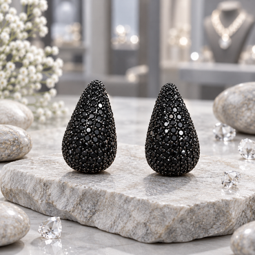 Pair of rounded black teardrop earrings with closely set round black accents, pointed tops and wider curved bases.
