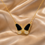 Black enamel and CZ pave butterfly pendant necklace in gold-tone finish with black upper wings and white cubic zirconia lower wings on fine gold cable chain displayed on golden satin