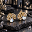 Pair of gold-tone cluster earrings with pink accents, sparkling openwork panels, rectangular details and white iridescent pearl-look centres.