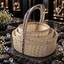 Three graduated cream-coloured round woven bucket baskets nested together, with reflective silver-tone rims and tall textured silver-tone arch handles.