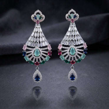 CZ Baguette Fan and Multicolour Sunburst Peacock Drop Earrings in Silver Multicolour worn by model in cream outfit with ornate backdrop close-up detail showing rhodium silver baguette cone fan peacock spoke fan with multicolour oval CZ accents and sapphire blue pear halo drop