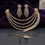 CZ Bridal Multi-Layer Drape Necklace Set with Starburst Brooch in Gold flat lay on dark surface with purple velvet backdrop showing 4-strand draped CZ tennis chains with twin starburst shoulder brooches matching tassel drop earrings and maang tikka in champagne gold-tone with white CZ