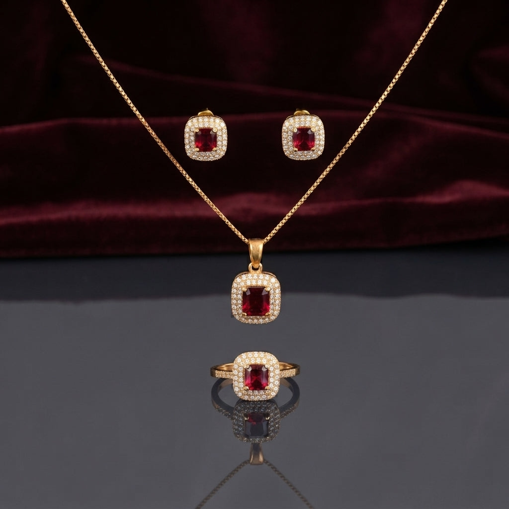CZ Cushion Halo Pendant Necklace Stud Earrings and Ring Set in Ruby Red CZ gold-tone flat lay on burgundy wine velvet backdrop showing 3-piece set with deep ruby red cushion CZ center in white CZ micro-pavé halo gold-tone pendant necklace matching stud earrings and cocktail ring with mirror reflection