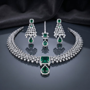 CZ Diamond Bridal Choker Necklace Earrings Maang Tikka Set in Royal Blue showing wide pave CZ tennis choker collar with large cushion and pear royal blue CZ centre pendant matching long chandelier earrings with geometric lattice panel and pear drop and maang tikka on dark mirror surface with charcoal satin backdrop