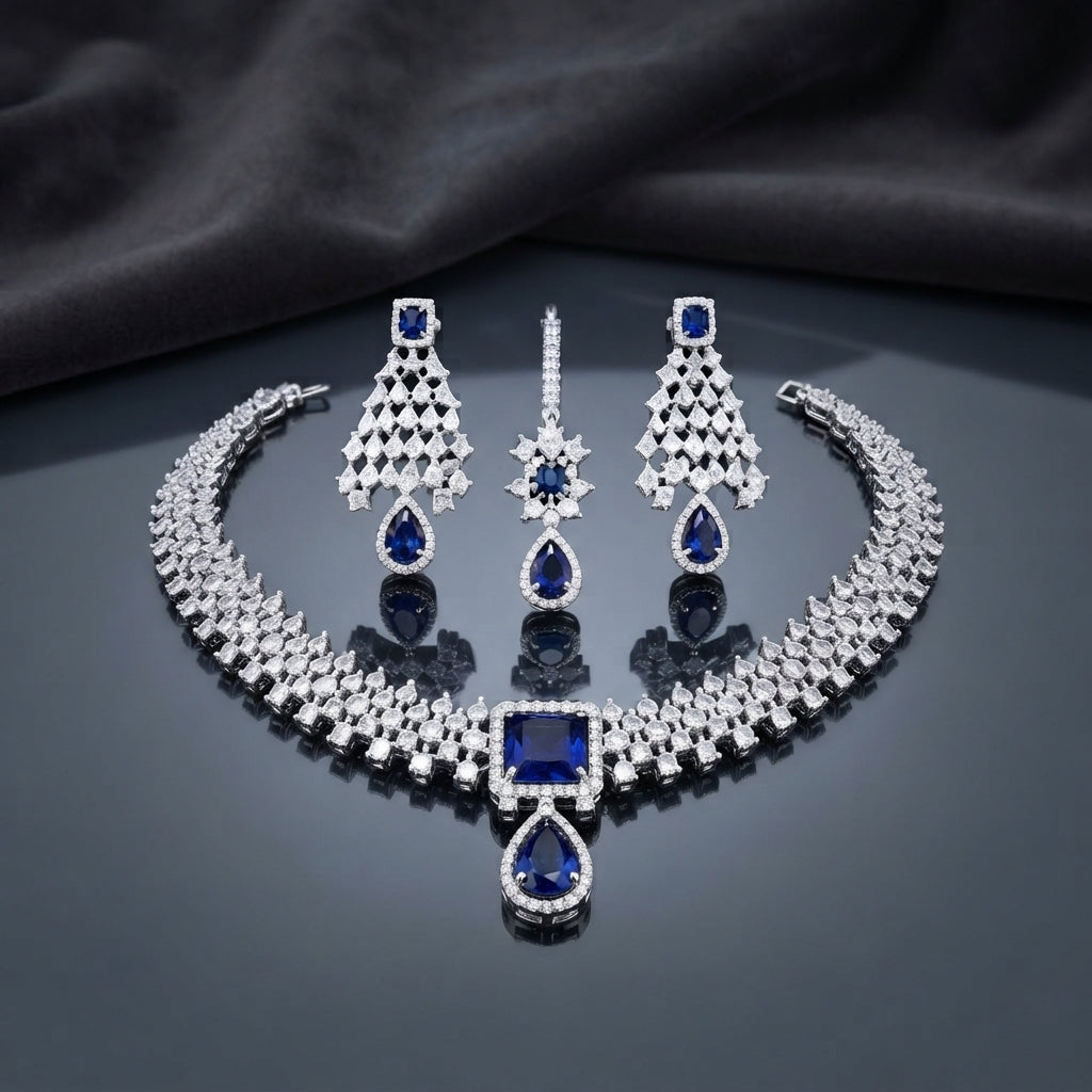 CZ Diamond Bridal Choker Necklace Earrings Maang Tikka Set in Emerald Green showing wide pave CZ tennis choker collar with large cushion and pear emerald green CZ centre pendant matching long chandelier earrings with geometric lattice panel and pear drop and maang tikka on dark mirror surface with charcoal satin backdrop