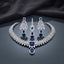 CZ Diamond Bridal Choker Necklace Earrings Maang Tikka Set in Emerald Green showing wide pave CZ tennis choker collar with large cushion and pear emerald green CZ centre pendant matching long chandelier earrings with geometric lattice panel and pear drop and maang tikka on dark mirror surface with charcoal satin backdrop
