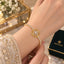 CZ Filigree Arabesque Medallion Centrepiece Round CZ Tennis Chain Bracelet in gold-tone worn on model wrist in bridal embroidered outfit with Destiny jewelry box and floral backdrop