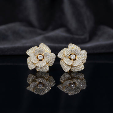 CZ Micro-Pavé 3D Camellia Rose Flower Stud Earrings in 22K Gold on black mirror surface with dark grey silk fabric backdrop