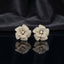 CZ Micro-Pavé 3D Camellia Rose Flower Stud Earrings in 22K Gold on black mirror surface with dark grey silk fabric backdrop