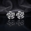 CZ Micro-Pavé 3D Camellia Rose Flower Stud Earrings in Black & Silver on black mirror surface with dark smoke fabric backdrop