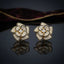 CZ Micro-Pavé 3D Camellia Rose Flower Stud Earrings in Gold & Black on dark mirror surface with deep burgundy velvet fabric backdrop