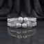 CZ Pave Ball Charm Multi-Row Open-Work Spine Bangle Pair in silver rhodium-tone finish displayed stacked on dark grey marble mirror surface with black silk drape backdrop showing two matching bangles with double-row chevron herringbone spine-rib lattice band continuous round CZ micro-pave and 4 large round CZ pave ball charms at center front with mirror reflection below