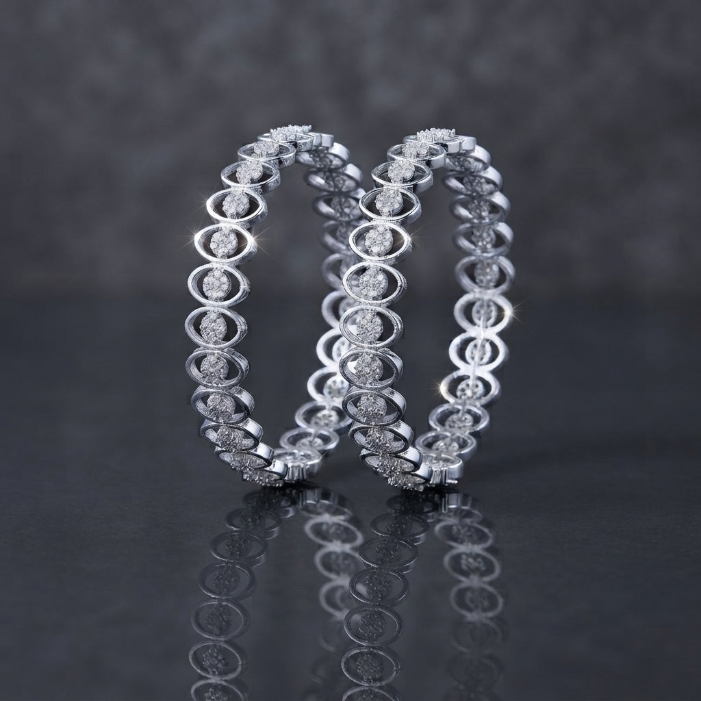 CZ Pave Flower Cluster Open-Oval Link Bangle Pair in gold-tone finish displayed leaning upright on dark grey mirror surface with cream fabric backdrop showing pair of matching bangles with continuous open-oval eye-shaped link band featuring round CZ micro-pave flower cluster centers with mirror reflection below