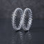 CZ Pave Flower Cluster Open-Oval Link Bangle Pair in gold-tone finish displayed leaning upright on dark grey mirror surface with cream fabric backdrop showing pair of matching bangles with continuous open-oval eye-shaped link band featuring round CZ micro-pave flower cluster centers with mirror reflection below