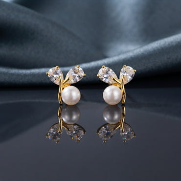 CZ Pear Leaf Branch Pearl Stud Earrings in Gold pair on dark slate mirror surface with grey silk backdrop showing 18K gold-tone slim Y-shaped branch stud with large pear-cut CZ and smaller round CZ as leaves cradling a lustrous round white pearl at the fork with mirror reflection below