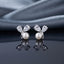 CZ Pear Leaf Branch Pearl Stud Earrings in Silver pair on dark slate mirror surface with grey silk backdrop showing rhodium-plated slim Y-shaped branch stud with large pear-cut CZ and smaller round CZ as leaves cradling a lustrous round white pearl at the fork with mirror reflection below