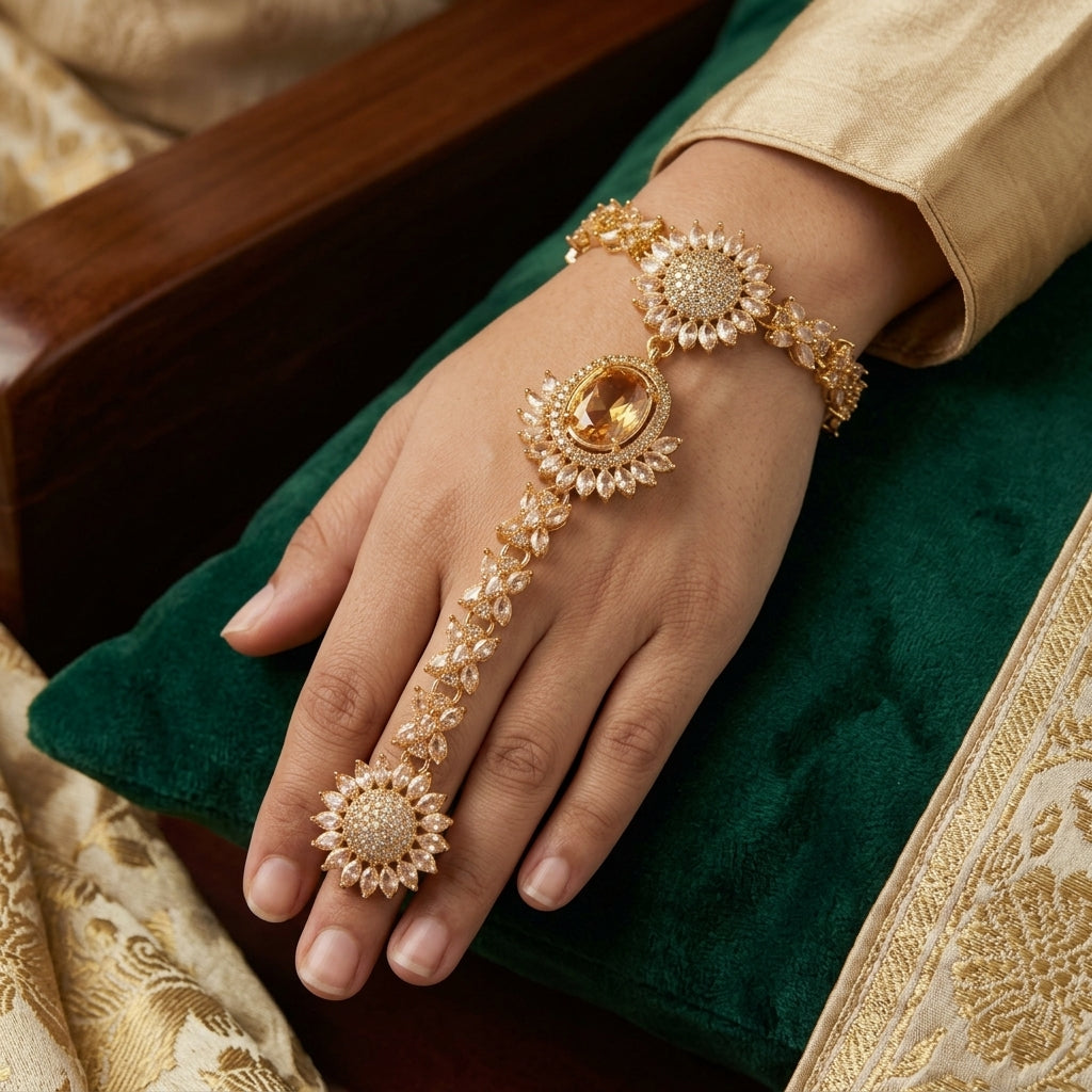 CZ Sunflower Cluster Hath Phool Hand Bracelet Ring Gold on dark mirror surface with burgundy velvet backdrop showing three sunflower cluster stations with champagne oval CZ centre micro-pave dome and marquise CZ petals in 18K gold-tone plating with mirror reflection below