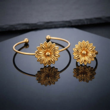 Gold 3D Lotus Dahlia Flower Open Cuff Bangle and Ring Matching Jewelry Set on dark grey slate surface with charcoal backdrop showing 22K warm matte yellow gold-tone open cuff wire bangle lying flat with matching open adjustable ring standing beside it both featuring 3D sculptural multi-layered lotus dahlia flowers with engraved spine petals and raised polished dome centres with mirror reflections below