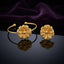 Gold 3D Sculptural Peony Flower Open Cuff Bangle Bracelet Set of 2 pair standing side by side on dark grey mirror surface with deep purple amethyst velvet backdrop showing 22K warm matte yellow gold-tone open cuff wire bangles each with large 3D sculptural multi-layered peony dahlia flower featuring herringbone feather-vein textured petals and raised polished dome centre with sharp mirror reflections below