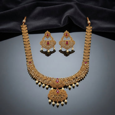 Gold Antique Ruby CZ Filigree Leaf Chain Necklace and Chandbali Earrings Set flat lay on burgundy wine velvet backdrop showing 2-piece set with long graduated filigree leaf-link chain necklace with scattered ruby CZ accents and double-tiered Mughal pendant with pearl fringe drops and matching Chandbali earrings