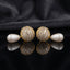 Gold-Tone Baguette CZ Globe Sphere Stud & Pearl Teardrop Drop Earrings on black mirror surface with dark grey silk fabric backdrop