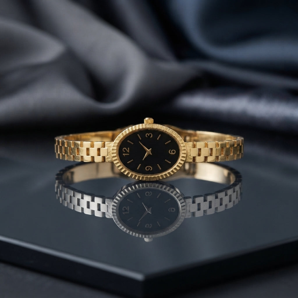 Gold Bangle Bracelet Watch with black dial on dark mirror surface with grey silk backdrop showing 18K gold-tone slim president-style 3-link bracelet with small oval case fluted bezel and black Arabic numeral dial with gold-tone hands with mirror reflection below